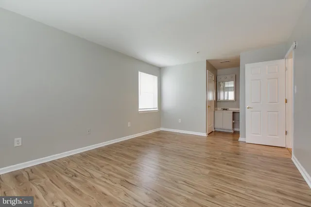 a view of an empty room with window and wooden floor