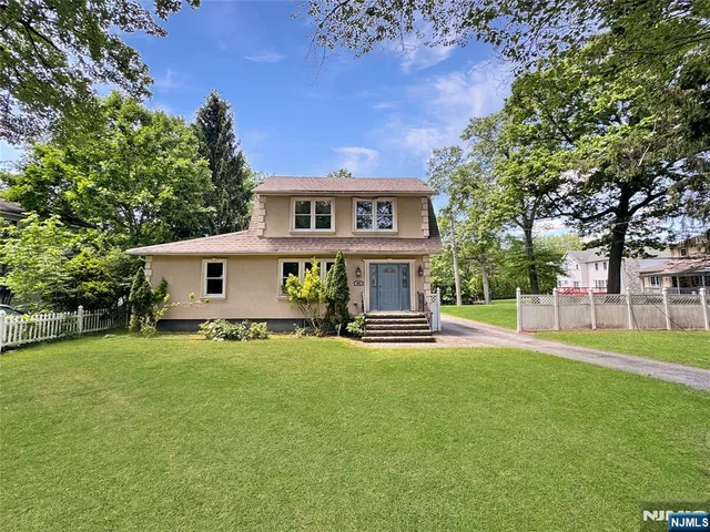a front view of a house with a garden and trees
