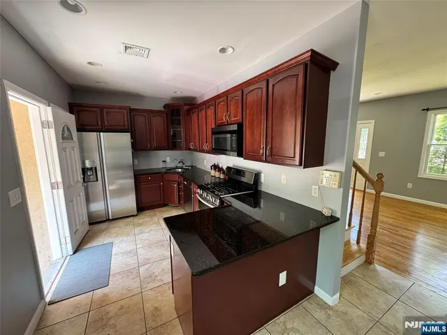 a kitchen with stainless steel appliances granite countertop a refrigerator a stove and a sink
