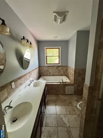 a bathroom with a tub sink and mirror