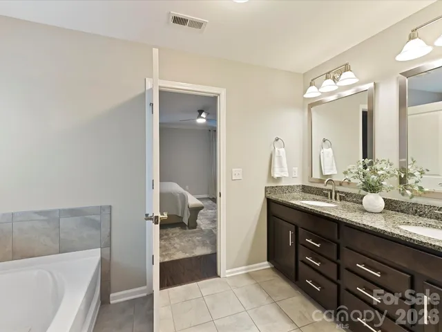 a spacious bathroom with a granite countertop sink mirror and bathtub
