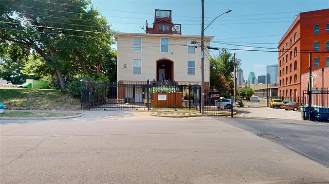 a view of a building with cars park side of road