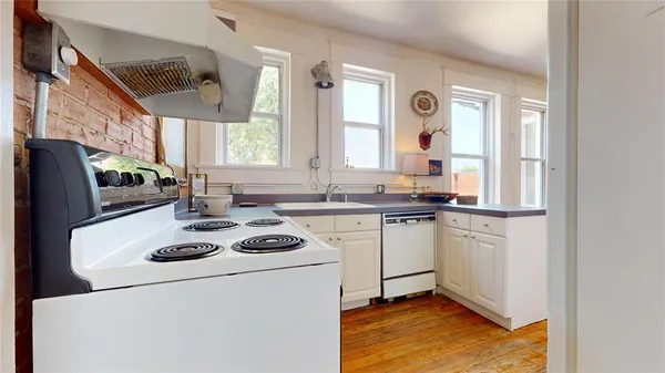 a kitchen with a refrigerator a stove a sink dishwasher and wooden cabinets with wooden floor