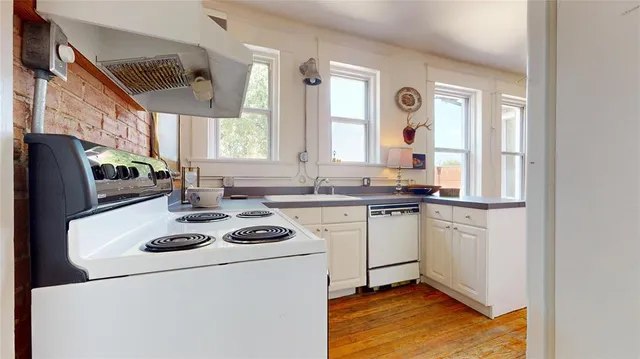 a kitchen with a refrigerator a stove a sink dishwasher and wooden cabinets with wooden floor