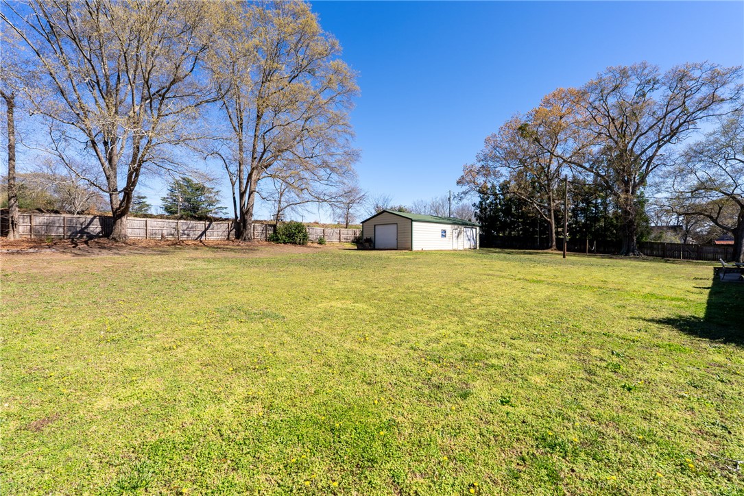 300 Green Street Williamston, SC 29697 - Photo 40 of 47 Expansive green yard with a functional outbuilding and surrounding natural privacy.