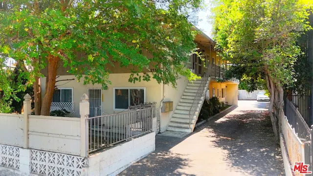 a view of a house with large tree and wooden fence