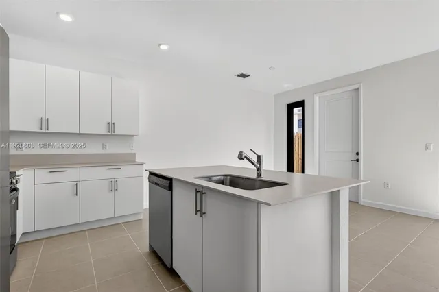 a kitchen with granite countertop white cabinets and a sink