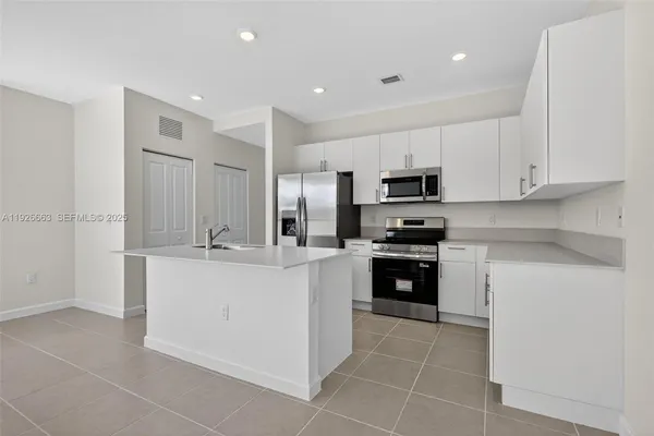 a kitchen with stainless steel appliances granite countertop a sink and white cabinets