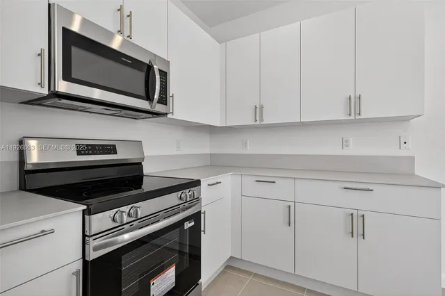 a kitchen with white cabinets and black appliances