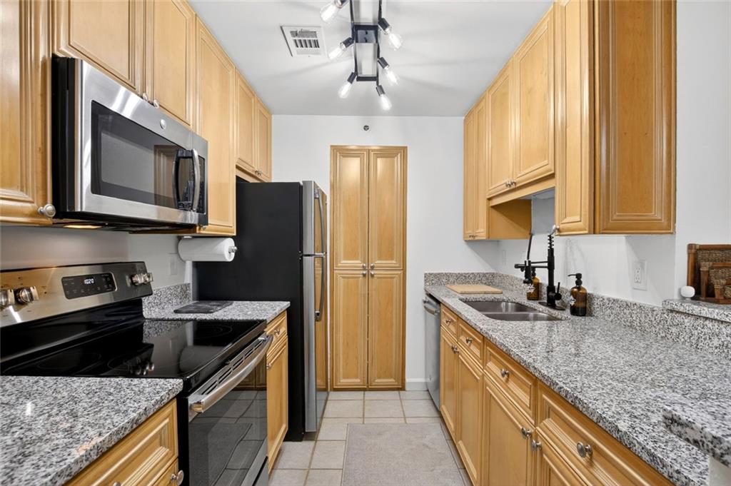 3203 Lenox Road Northeast, Unit 32 Atlanta, GA 30324 - Photo 17 of 38 a kitchen with stainless steel appliances granite countertop a sink stove and refrigerator