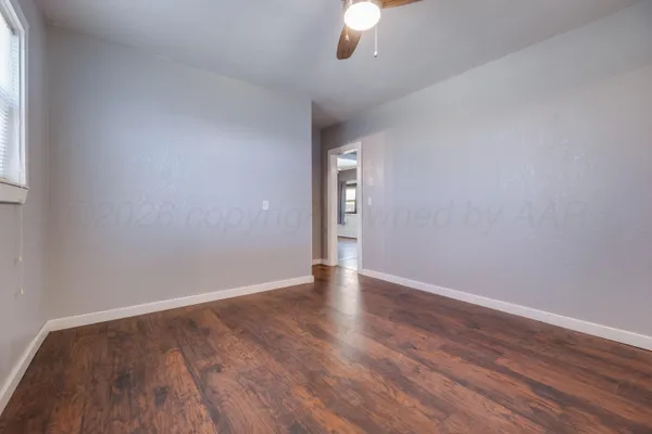 a view of an empty room with wooden floor and a window