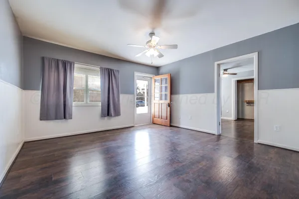 a view of an empty room with window and wooden floor
