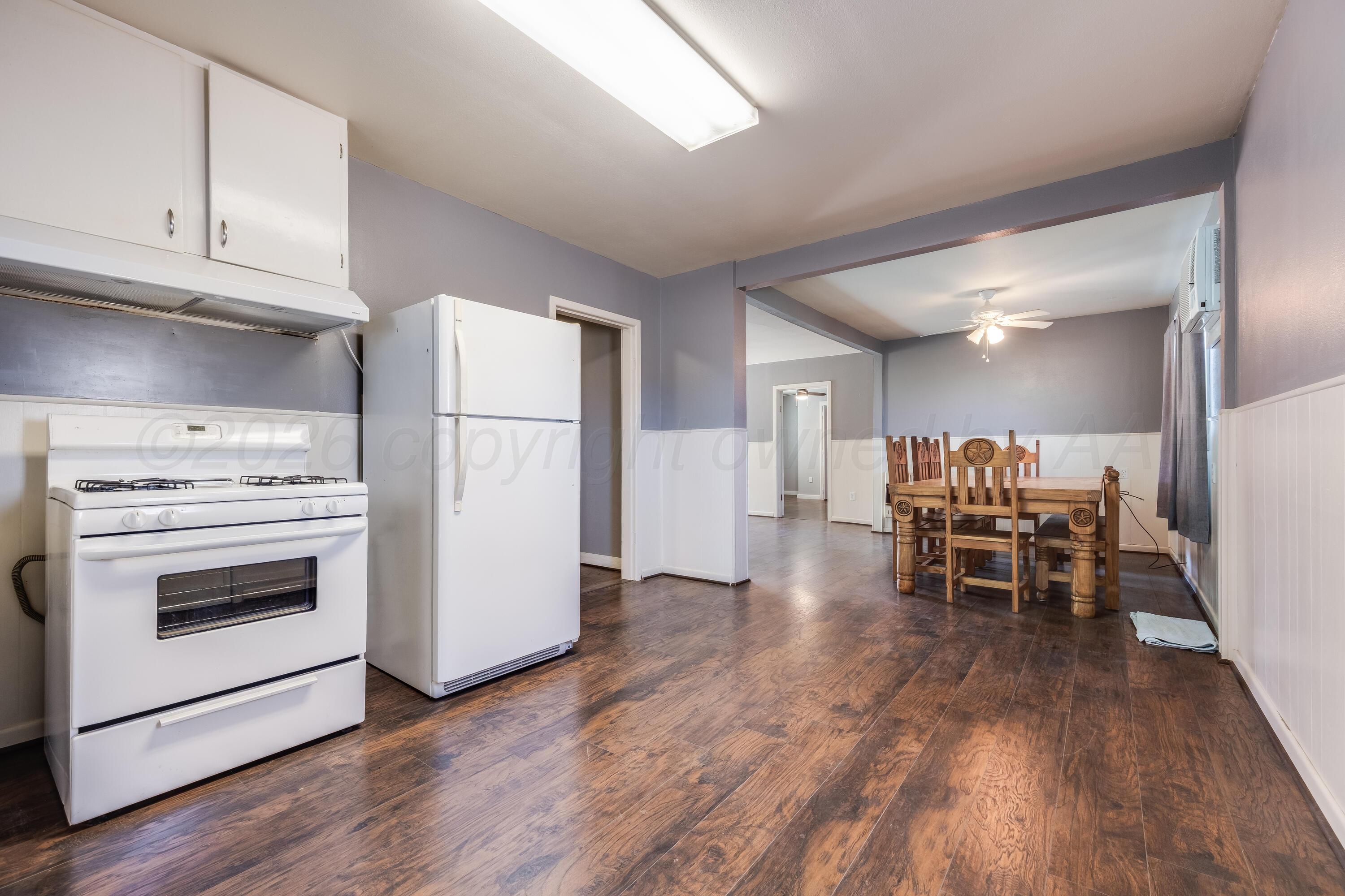 102 Lee Avenue Allison, TX 79011 - Photo 10 of 30 a kitchen with a white stove top oven and chairs