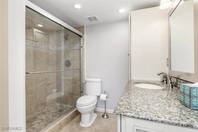 a bathroom with a granite countertop sink a toilet and shower
