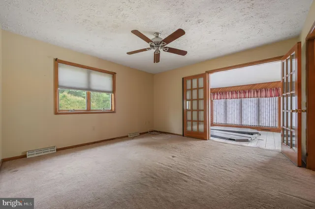 an empty room with windows and ceiling fan