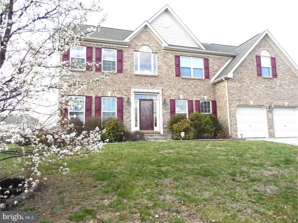 a view of a brick house with a big yard and large trees