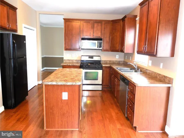 a kitchen with stainless steel appliances granite countertop wooden cabinets a sink a stove a washer and dryer