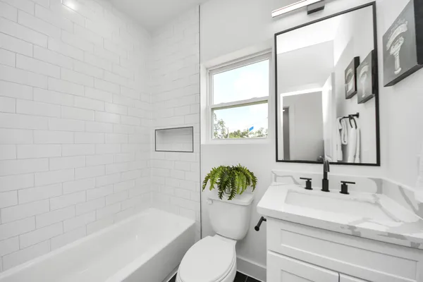 a bathroom with a granite countertop sink toilet a mirror and a bathtub