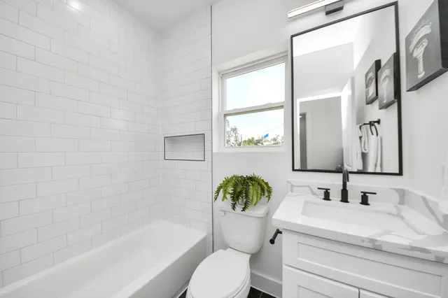a bathroom with a granite countertop sink toilet a mirror and a bathtub