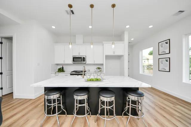a kitchen with stainless steel appliances kitchen island granite countertop a table chairs sink and cabinets