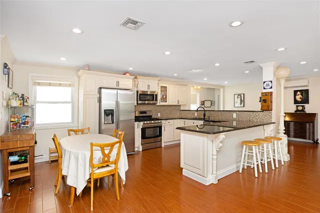 a kitchen with stainless steel appliances kitchen island granite countertop a dining table chairs and refrigerator