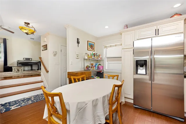 a kitchen that has a refrigerator a stove and a dining table with wooden floor