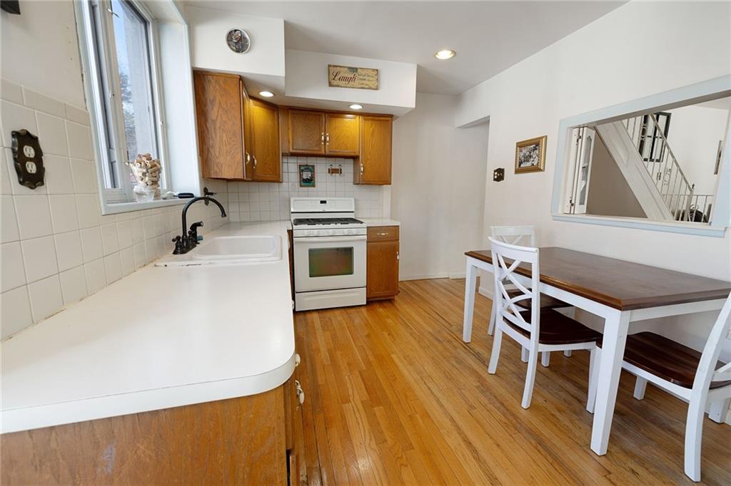 25 89th Street Brooklyn, NY 11209 - Photo 9 of 20 a kitchen with stainless steel appliances a stove a sink a microwave a refrigerator white cabinets and wooden floor