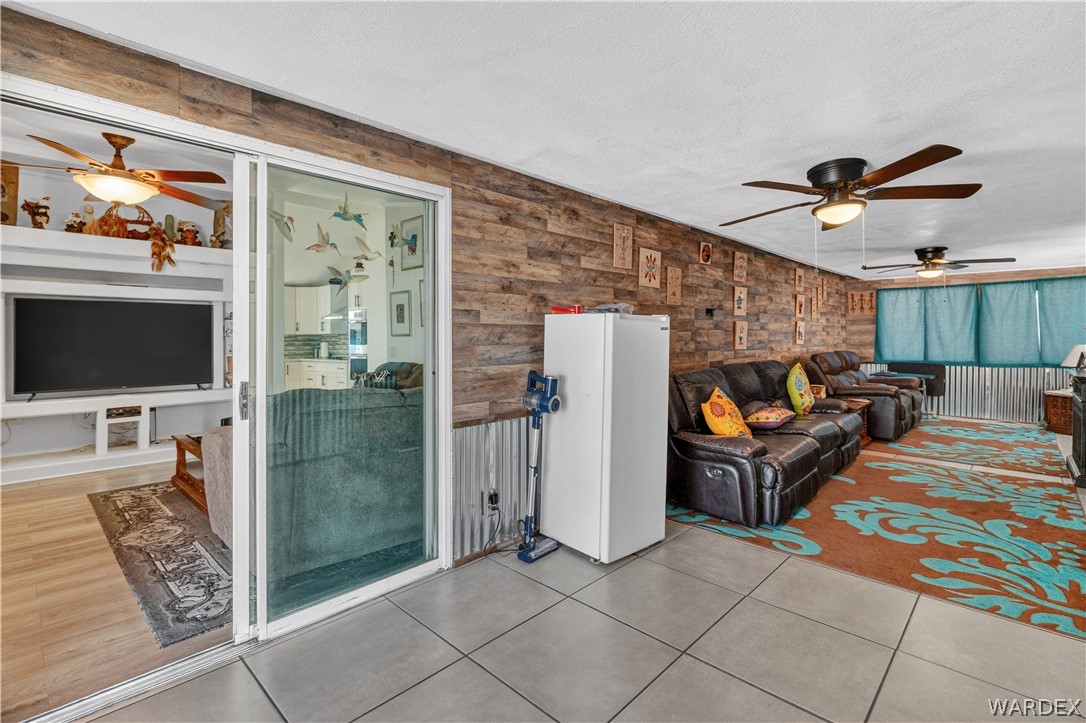 784 Pegasus Ranch Road Bullhead City, AZ 86429 - Photo 49 of 100 Spacious room featuring wood-finish accent wall, ceiling fans, and large format tile flooring