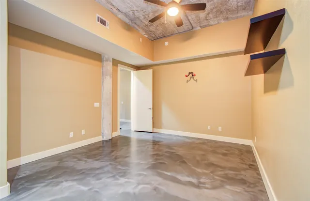 an empty room with a chandelier fan and windows