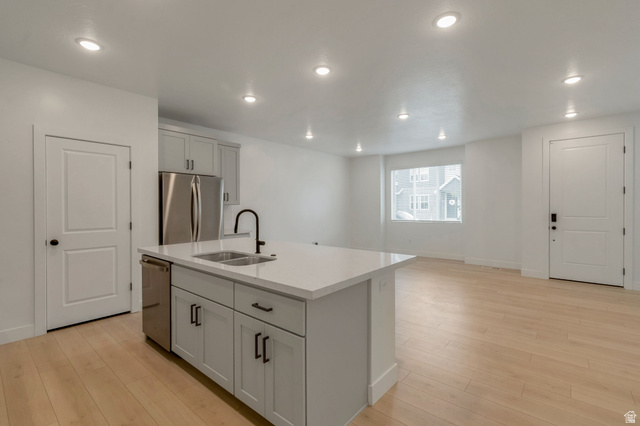 30 South Moonlit Road Mapleton, UT 84664 - Photo 5 of 25 Kitchen island with an undermount double-basin sink and matte black faucet, light wood-finish flooring, recessed lighting, and stainless steel appliances