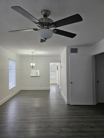 a view of a livingroom with a ceiling fan wooden floor and window