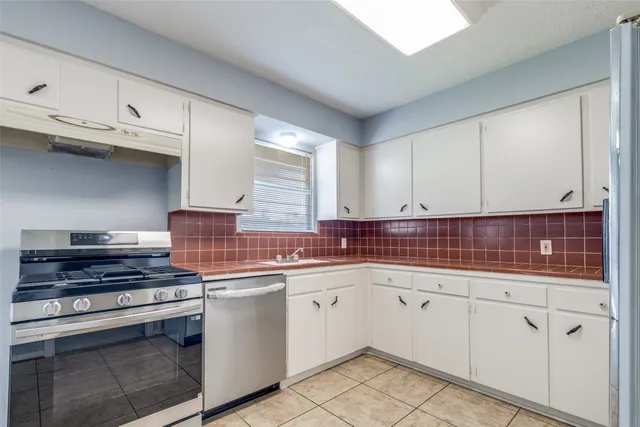 a kitchen with white cabinets and appliances
