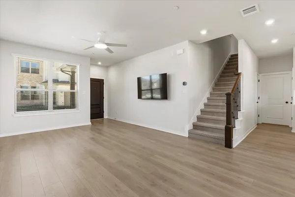 an empty room with wooden floor and windows