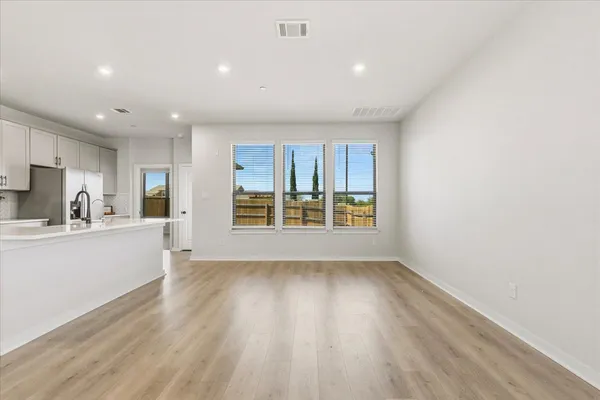 a view of kitchen with stainless steel appliances refrigerator oven and white cabinets with wooden floor