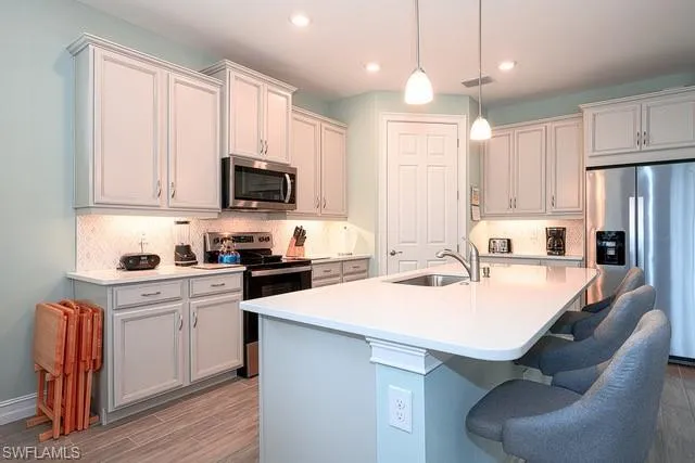 a kitchen with a sink a stove a refrigerator and white cabinets