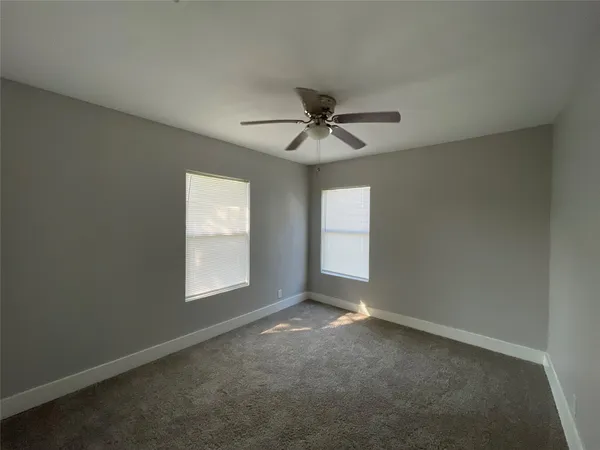 an empty room with windows and ceiling fan