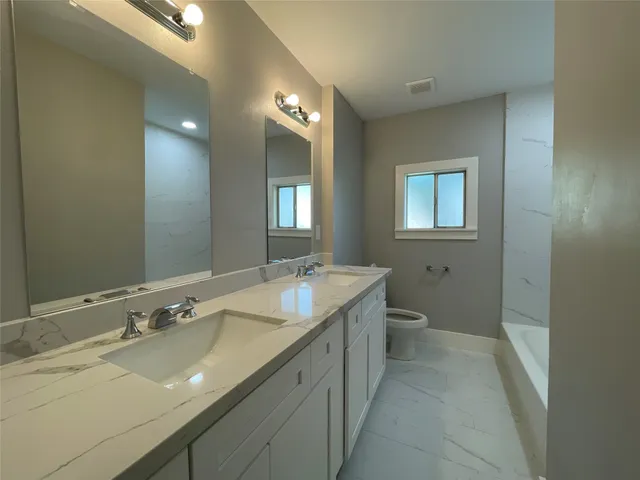 a bathroom with a granite countertop sink mirror and toilet