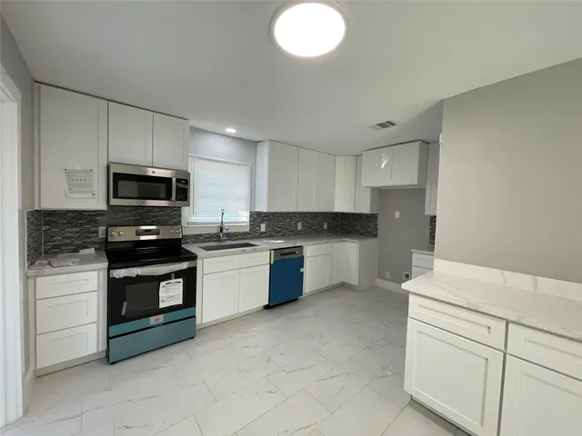 a kitchen with stainless steel appliances granite countertop a stove a sink and a microwave