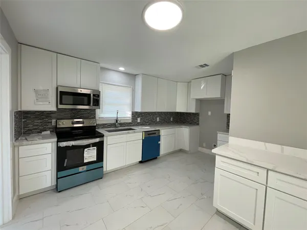 a kitchen with stainless steel appliances granite countertop a stove a sink and a microwave