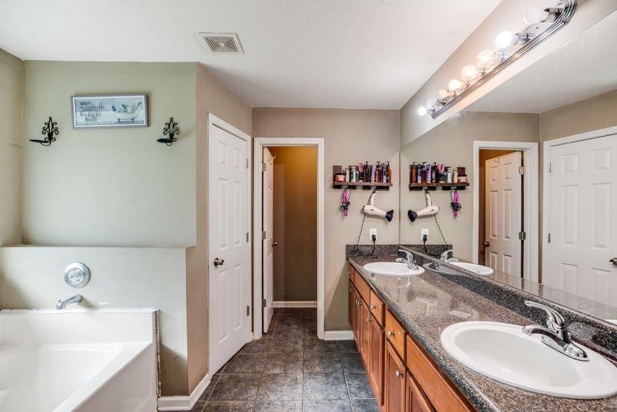43 Mimosa Street Buchanan, GA 30113 - Photo 26 of 33 a bathroom with a granite countertop double vanity sink a mirror and a bathtub