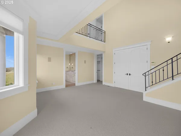 a view of an empty room with window and stairs