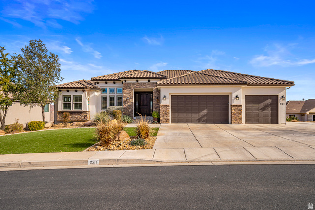 2311 South 1340 West St. George, UT 84770 - Photo 2 of 56 Mediterranean / spanish-style house with stone siding, an attached garage, driveway, stucco siding, and a front lawn