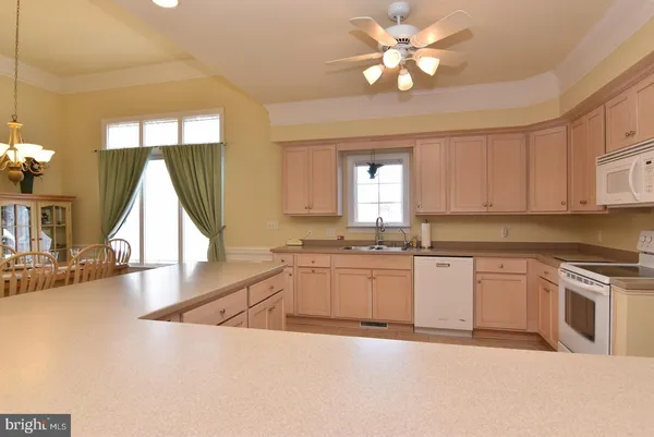 a kitchen with granite countertop a stove a sink and white cabinets with wooden floor