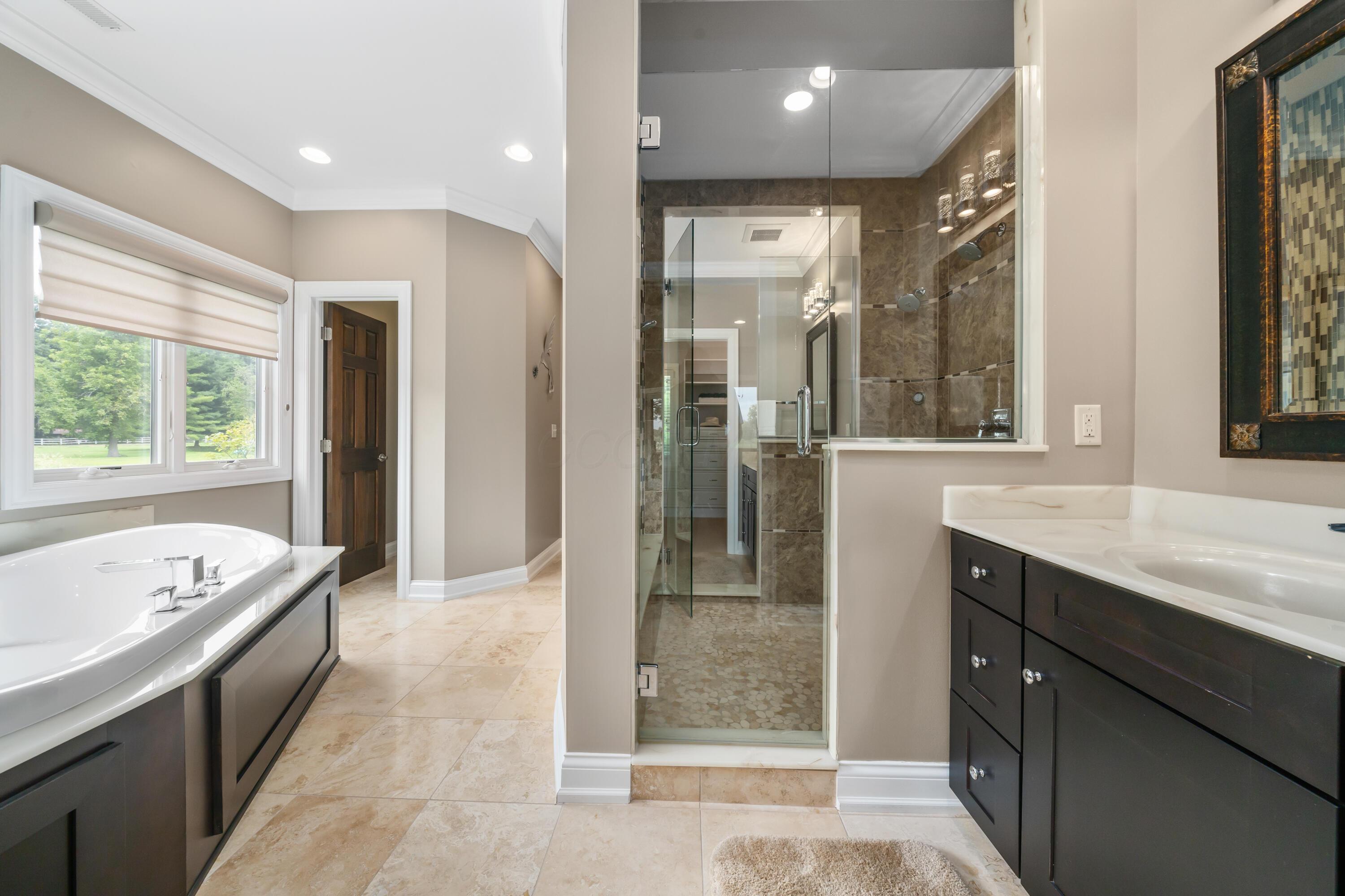 4640 Maynard Road Delaware, OH 43015 - Photo 34 of 91 Contemporary bathroom featuring a freestanding tub with deck-mounted fixtures, a glass-enclosed shower with full-height tile, and a dark wood vanity with a white countertop and undermount sink
