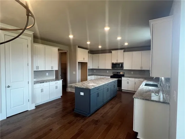 a kitchen with granite countertop a stove top oven and cabinets
