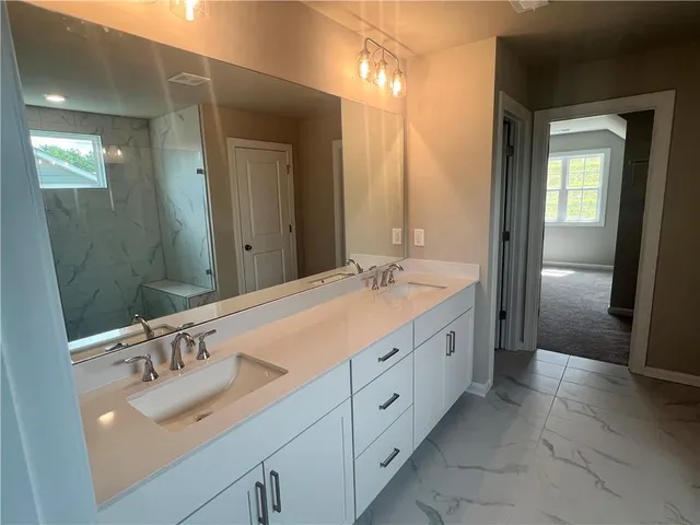 a spacious bathroom with double sink and mirror