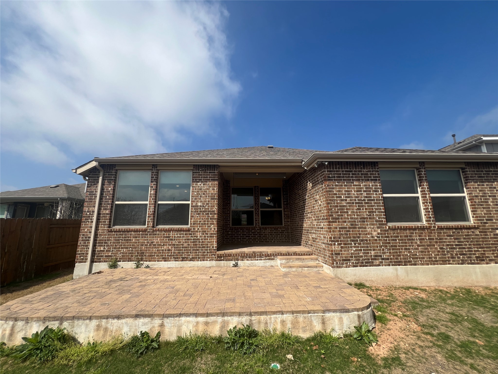 7009 Sienna Rouge Path Austin, TX 78744 - Photo 18 of 29 View of front facade featuring a patio area, brick siding, and a shingled roof