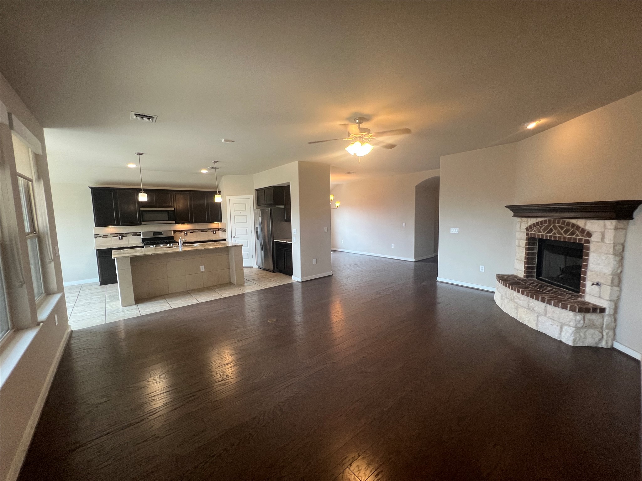 7009 Sienna Rouge Path Austin, TX 78744 - Photo 2 of 29 Unfurnished living room featuring a fireplace with raised hearth, recessed lighting, a ceiling fan, and light wood-type flooring