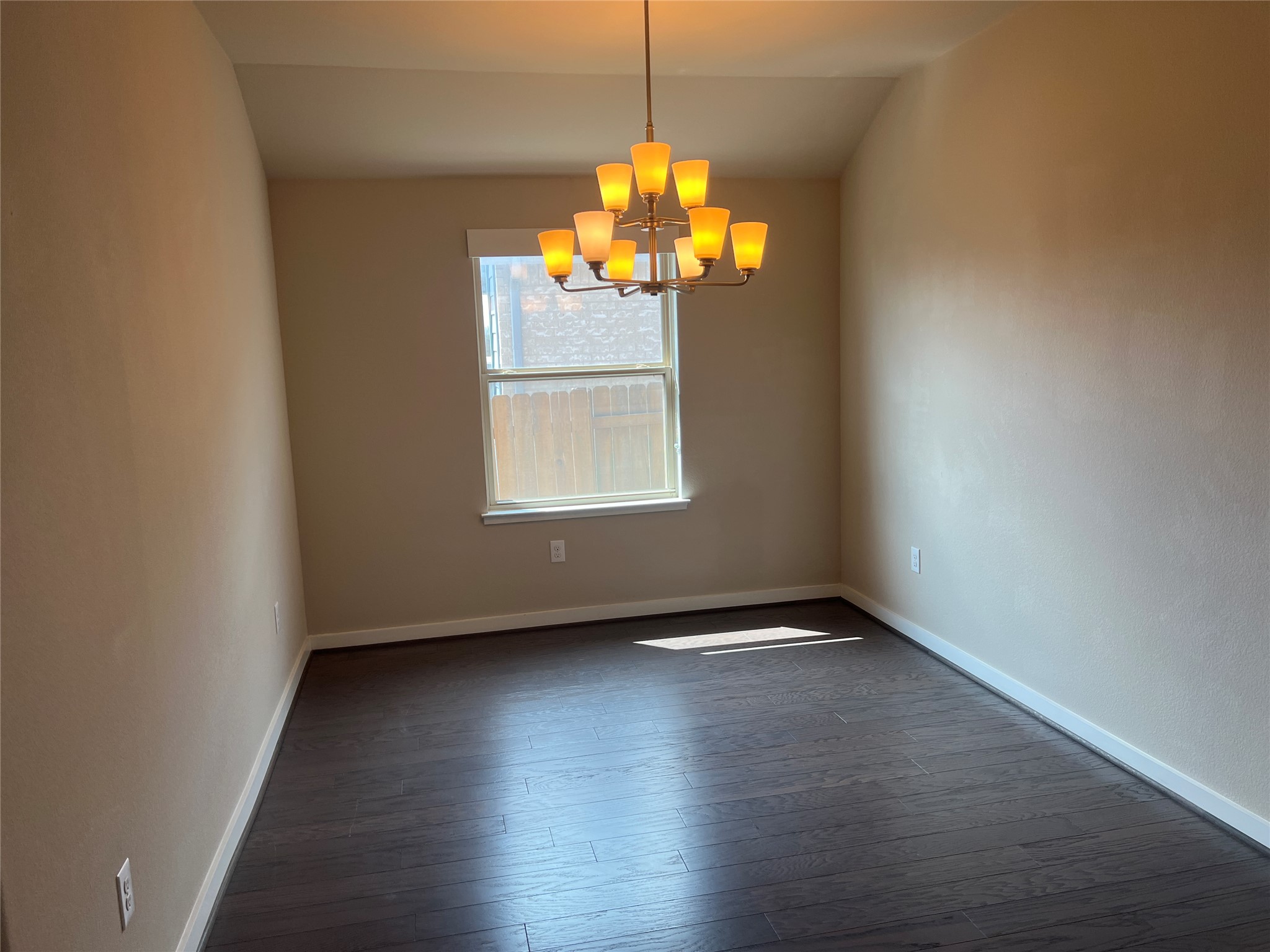 7009 Sienna Rouge Path Austin, TX 78744 - Photo 6 of 29 Unfurnished room featuring hanging lights and dark wood-style floors