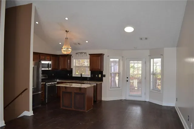 an empty room with wooden floor and a kitchen